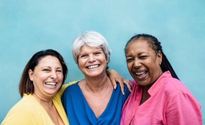 Three women of different ethnicities posing and smiling 